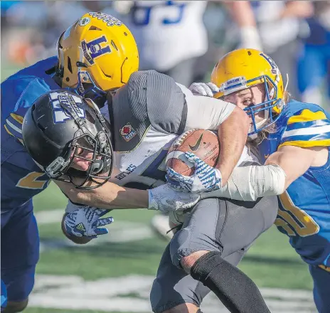  ?? KAYLE NEIS ?? Winnipeg Rifles receiver Brendan Naujoks is tackled by Hilltops defensive back Logan Bitz, left, and Hilltops linebacker Adam Benkic during their game at SMF Field in Saskatoon on Sunday.