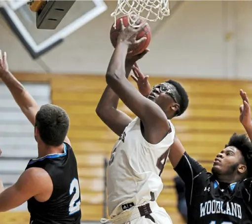  ?? Pam Panchak/Post-Gazette ?? Ambridge’s Enire Bowens goes up for a basket against Woodland Hills’ Gavin Judson and Raelon Robertson in the Midland Tournament at Geneva College Friday, Dec. 7 in Beaver Falls. Bowens and Ambridge dropped the first game of the season, a 67-65 loss in overtime.