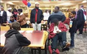  ?? EVAN BRANDT — MEDIANEWS GROUP ?? New Pottsgrove High School graduate JaSaad Jamison, seated, is congratula­ted by his father, Sadiki West, behind him, and other family members during a reception in the library following the special graduation ceremony Thursday.