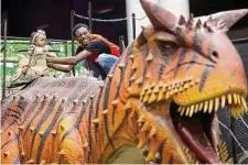  ?? Photos by Annie Mulligan / Contributo­r ?? Aurtrel Black gives 1-year-old Juliana Newkirk a hand on top of one of the dinosaurs at “Jurassic Quest.”