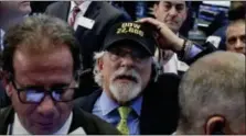  ?? RICHARD DREW — THE ASSOCIATED PRESS ?? Trader Peter Tuchman, center, wears a “Dow 22,000” hat as he works on the floor of the New York Stock Exchange, Wednesday.