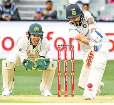  ??  ?? India’s captain Virat Kohli plays a defensive shot as Australian wicketkeep­er Tim Paine looks on during the day one of the first cricket Test match between Australia and India in Adelaide. - AFP photo