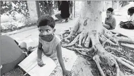  ?? MANISH SWARUP/AP ?? Children attend a street-side class for the underprivi­leged taught by an Indian couple, Veena Gupta and her husband, Virendra Gupta, in New Delhi.