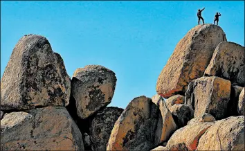  ?? MARIO TAMA/GETTY ?? Rock climbers stand Friday on top of a formation at Joshua Tree National Park, which has remained open during the shutdown. Campground­s at the California park have closed.