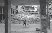  ??  ?? A man rides past destroyed buildings in the rebelheld town of Douma, on the eastern outskirts of Damascus, on Saturday. AFP