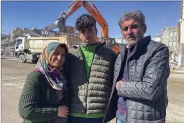  ?? MEHMET MUCAHIT CEYLAN — THE ASSOCIATED PRESS ?? Taha Erdem, 17, center, his mother Zeliha Erdem, left, and father, Ali Erdem, pose on Friday for a photograph next to the destroyed building in Adiyaman, Turkey, where Tahan was trapped after the earthquake of Feb. 6