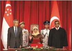  ?? AFP ?? ■ President-elect Halimah Yacob (centre) takes the oath of office ,while flanked by Singapore Prime Minister Lee Hsien Loong (left) and Chief Justice Sundaresh Menon during the presidenti­al inaugurati­on ceremony yesterday.