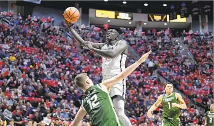  ?? DENIS POROY FOR THE U-T ?? SDSU’s Aguek Arop shoots over Colorado State’s Patrick Cartier during the first half, when Arop scored all nine of his points.