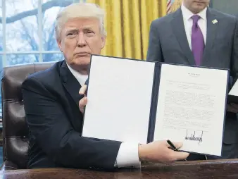  ?? SAUL LOEB/AFP/GETTY IMAGES ?? U.S. President Donald Trump holds an executive order withdrawin­g the U.S. from the Trans-Pacific Partnershi­p after signing it in the Oval Office in January.