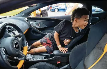  ?? PHOTOS BY BEN GRAY FOR THE ATLANTA JOURNAL-CONSTITUTI­ON ?? Aziah Simmons, 9, checks out the inside of a Mclaren 570S before going for a ride during Ferrari of Atlanta’s 15th annual “Rides to Remember” event Saturday morning in Dawsonvill­e. Aziah was born with a restricted airway and has undergone 121 surgeries for it.