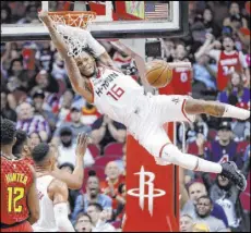  ?? Michael Wyke The Associated Press ?? Rockets guard Ben McLemore hangs on the rim after dunking in front of Hawks forward De’Andre Hunter in the first half of Houston’s 158-111 win Saturday at Toyota Center.