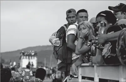  ?? REBECCA BLACKWELL AP PHOTO ?? Migrants hitch a ride on a truck as they continue their journey after police briefly blockaded the road to keep them from advancing, outside the town of Arriaga on Saturday. Mexican federal officers briefly blocked the caravan of Central American migrants from continuing toward the United States, after many of them rejected the chance to apply for refugee status and obtain a Mexican offer of benefits. HITCHING A RIDE