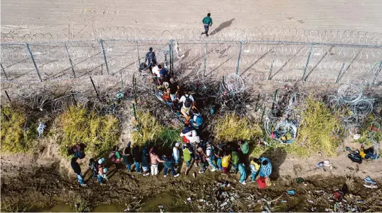  ?? John Moore/Getty Images ?? Texas hasn’t eliminated illegal border crossings; it’s simply slowed them by about 30%. In March, immigrants passed through coils of razor wire in El Paso.