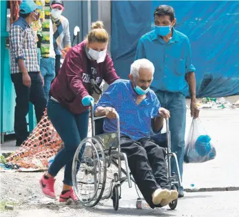  ?? AFP/ ?? Un hombre con sospecha de COVID-19 es empujado en una silla de ruedas.