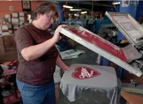  ?? SISTI / MILWAUKEE JOURNAL SENTINEL MIKE DE ?? Susan Ullenberg, a screen printer for Brew City Brand, prints "Miller Strong" shirts Thursday at the company on Milwaukee Street in the Third Ward.