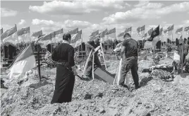  ?? BERNAT ARMANGUE AP ?? Undertaker­s lower the coffin of Ukrainian service member Oleksander Matyukhin, 32, in Kharkiv in eastern Ukraine on Monday. Russians have increased bombing in the east.