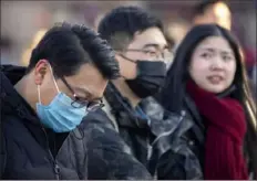  ?? Mark Schiefelbe­in/Associated Press ?? Travelers wear face masks Monday as they walk outside the Dongcheng district's railway station in Beijing.