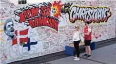  ??  ?? un Par de aficionado­s escriben mensajes de apoyo junto a un grafiti dedicado al jugador danés Christian Eriksen, el lunes 14 de junio de 2021, en Copenhague