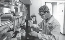  ?? ZHANG YUWEI / XINHUA ?? A CNBG employee performs tests on the company’s COVID-19 vaccines under developmen­t at a research institute in Wuhan, capital of Hubei province, on April 11.