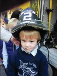 ??  ?? Thomas Lynn of Newtown Square tries on a firefighte­r’s helmet to see if it fits.