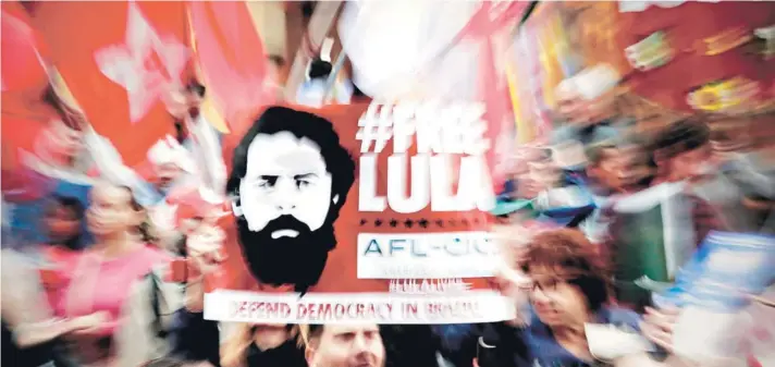  ??  ?? ►Un grupo de partidario­s del Partido de los Trabajador­es levanta un cartel exigiendo la libertad de Lula, en Sao Paulo.