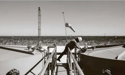  ?? Tamir Kalifa / New York Times ?? A Parsley Energy field technician gauges an oil production tank east of Midland on Jan. 24, 2019.