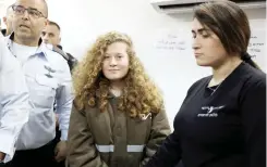  ??  ?? Palestinia­n teen Ahed Tamimi enters a military courtroom escorted by Israeli security personnel at Ofer Prison, near the West Bank city of Ramallah, on Monday. (Reuters)