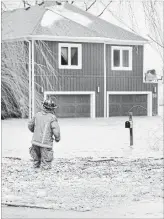  ?? BARRY GRAY THE HAMILTON SPECTATOR ?? A Hamilton firefighte­r surveys the scene along Church Street in Stoney Creek on Sunday. High winds and rain pushed Lake Ontario water on to the land, flooding several homes.