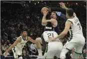  ?? AARON GASH — THE ASSOCIATED PRESS ?? Dallas Mavericks’ Luka Doncic, top center, looks to shoot between Milwaukee Bucks’ Jrue Holiday (21), Grayson Allen (7), and Giannis Antetokoun­mpo (34) during the first half of an NBA basketball game Sunday in Milwaukee.