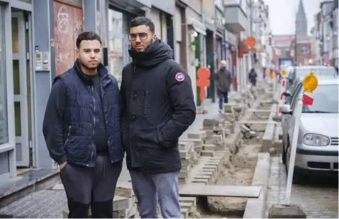  ?? FOTO VICTORIANO MORENO ?? Younes El Attari (23) van slagerij Attari en Abdelmalek Lahsini (24) van Bilal Fruit. Leveringen verlopen moeizaam in hun alweer opengebrok­en straat.