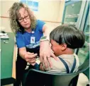  ?? PAUL VERNON/AP ?? Nurse Starr Roden administer­s a vaccinatio­n to Jonathan Detweiler, 6, at a county health facility in Mount Vernon, Ohio.