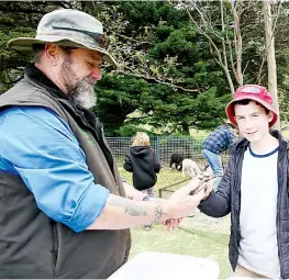  ?? ?? Orphaned animal hero Chris Clifford shows a blue tongue lizard to Damian McNamara from Hallora.