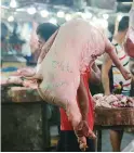  ?? PHILIPPINE STAR/MICHAEL VARCAS ?? A WORKER carries pork at Commonweal­th Public Market.