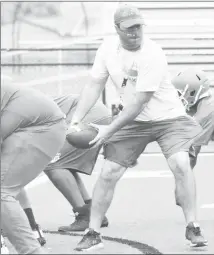  ?? Fred Conley • Times-Herald ?? Forrest City Junior Mustang coach Chris Siler takes the handoff as his team works through an offensive scrimmage in a practice held earlier this week.