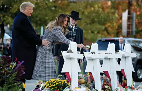  ?? Associated Press ?? ■ First lady Melania Trump, accompanie­d by President Donald Trump, and Tree of Life Rabbi Jeffrey Myers, right, puts down a white flower Tuesday at a memorial for those killed at the Tree of Life Synagogue in Pittsburgh.