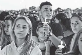  ?? JIM RASSOL/SOUTH FLORIDA SUN-SENTINEL VIA AP ?? Mourners gather Thursday at a vigil held for the victims of the shooting at Marjory Stoneman Douglas High School, in Parkland, Fla.