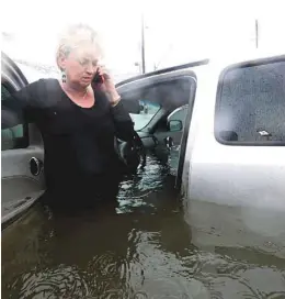 ?? LM OTERO ASSOCIATED PRESS ?? Une femme, convaincue de pouvoir s’avancer dans une rue inondée, tente d’obtenir du secours après avoir été surprise par la profondeur de l’eau.