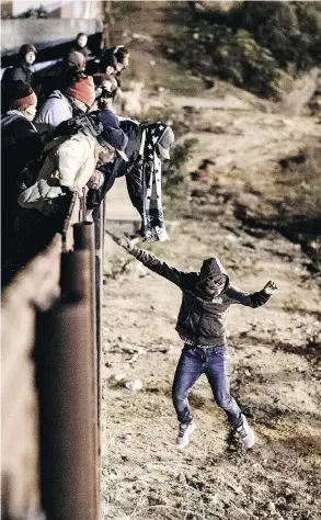  ?? DANIEL OCHOA DE OLZA / THE ASSOCIATED PRESS ?? A migrant jumps the border fence to get into San Diego from Tijuana on Tuesday.