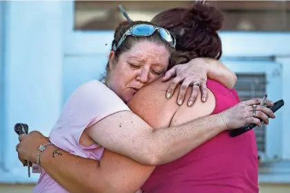  ?? NICK WAGNER, AUSTIN AMERICAN-STATESMAN / AP ?? Carrie Matula embraces a woman after a fatal shooting at the First Baptist Church in Sutherland Springs, Texas, on Sunday. Matula said she heard the shooting from the gas station where she works a block away.