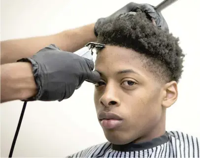  ?? PHOTOS BY MARIA DE LA GUARDIA/ SUN- TIMES ?? Isaiah Hoskins gets a clean edge shaved on Monday at the Austin library. He is one of many youths who showed up for a free haircut, supplied by the Fades for Days program.