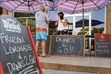  ?? AP ?? The Old Crow bar in Dallas sells drinks to go outside. While more states and cities are allowing carry-out drinks, critics worry it might result in an uptick in drunken driving.