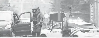  ??  ?? ANGGOTA skuad pemusnah bom memeriksa kereta suspek yang memaparkan plat nombor Jerman di Molenbeek, Brussels kelmarin. — Gambar AFP