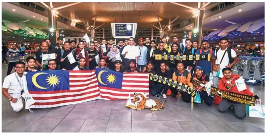  ??  ?? The faithfulon­es: Malaysian fans posing for a photograph in Kuala Lumpur Internatio­nal Airport yesterday ahead of the AFF Suzuki Cup final against Vietnam.