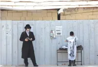  ?? (Nati Shohat/Flash90) ?? A JEWISH MAN and a young boy pray outside a synagogue in the Jewish settlement of Beitar Illit, in April.