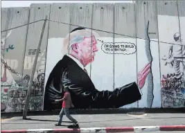  ?? Nasser Nasser ?? The Associated Press A mural resembling the work of elusive artist Banksy depicting President Donald Trump wearing a Jewish skullcap is seen Friday on Israel’s West Bank separation barrier in the West Bank city of Bethlehem.