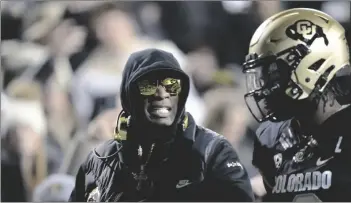  ?? AP PHOTO/DAVID ZALUBOWSKI ?? Colorado coach Deion Sanders (left) talks to quarterbac­k Shedeur Sanders, his son, during the first half of the team’s NCAA college football game against Stanford on Friday in Boulder, Colo.