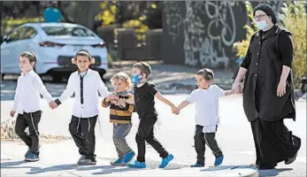  ?? KATHY WILLENS/AP ?? A group crosses a street last week in the Brooklyn borough of New York. Brooklyn has seen a rise in infections.