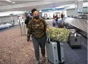  ?? Kevin Hagen / Associated Press ?? U.S. Navy member Estfhi Guzman picks up her baggage after landing Tuesday at New York City’s LaGuardia Airport.