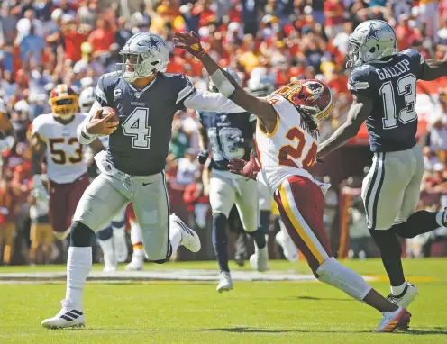  ?? ALEX BRANDON/ASSOCIATED PRESS ?? Cowboys quarterbac­k Dak Prescott, left, stiff-arms Redskins cornerback Josh Norman on Sunday in Landover, Md. Prescott scampered for 69 yards and threw three touchdowns in a 31-21 win over Washington.