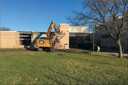  ?? RICHARD PAYERCHIN — THE MORNING JOURNAL ?? A worker prepares a hose to wet down dust as an excavator claws away at the brick facade to commence demolition Nov. 4at the west building of the former St. Joseph Community Center, 205W. 20th St., Lorain.